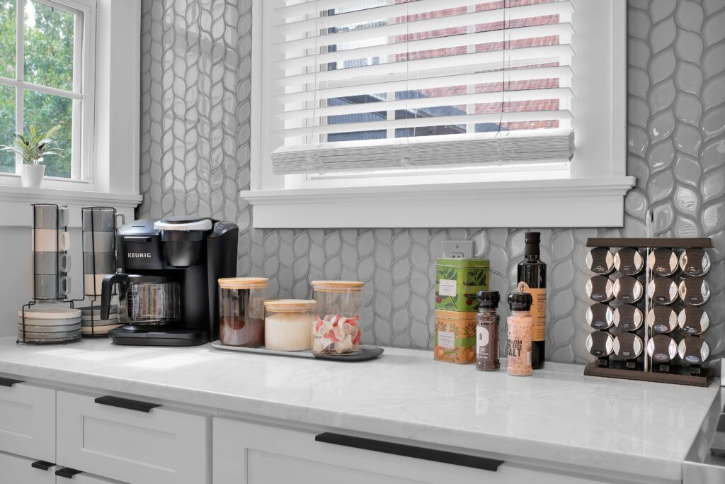 A Keurig coffee maker sits atop a kitchen countertop surrounded by cabinetry, drawers, and a kitchen sink with a tap.