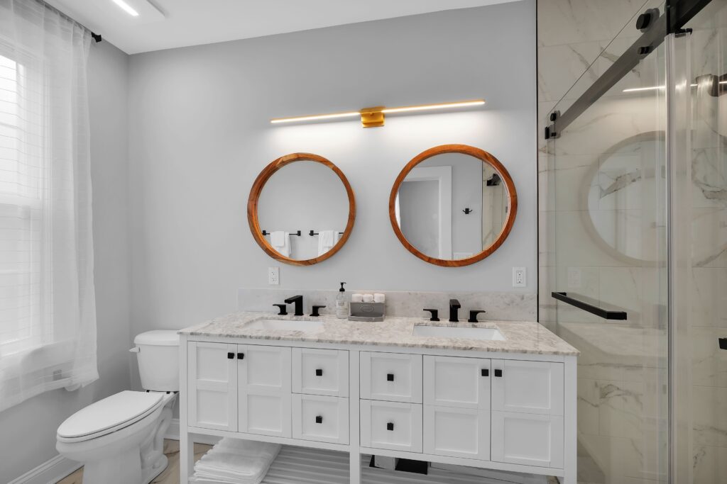A white bathroom with a shower, toilet, sink, tap, cabinetry, tile, countertop, mirror, and plumbing fixtures creates a modern interior design in the restroom.
