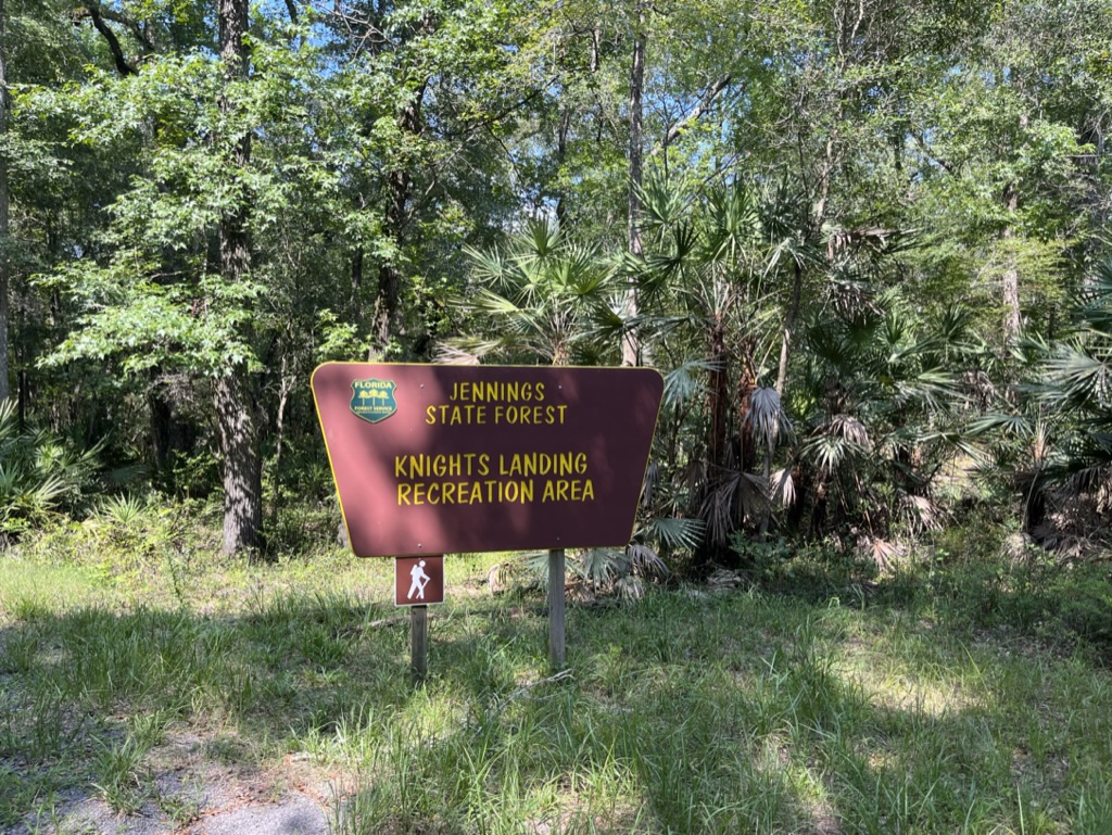 The sign stands in the woods.